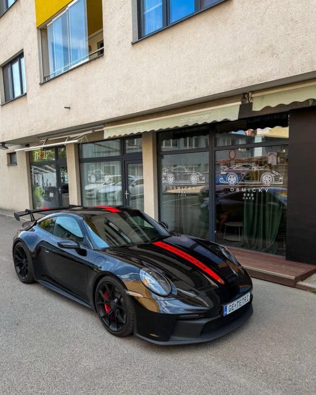 Čierne Porsche s pretekárskym krídlom zaparkované pred kaviarňou Osmičky 888 v Trenčíne